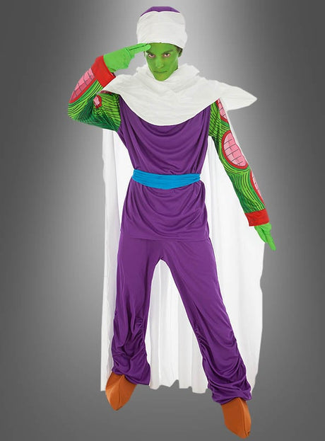 Eine Person, die das Dragon-Ball-Kostüm von Piccolo trägt – mit grüner Gesichtsbemalung, einem violetten Outfit, einem weißen Umhang und einem blauen Gürtel –, posiert mit einer Hand an der Stirn vor einem grauen Hintergrund.
