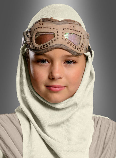 Ein junger Mensch, der die „Star Wars 7 Rey“-Brille mit Kapuze für Kinder trägt – mit einer strukturierten weißen Kapuze und hellbraunen Schutzbrillen –, posiert mit ausdruckslosem Gesicht vor einem grauen Hintergrund.