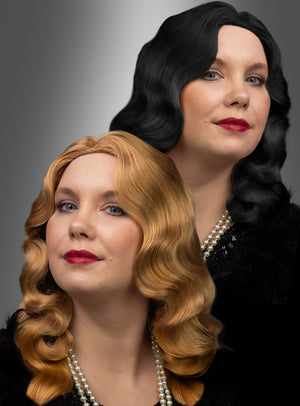 Zwei Frauen mit welligem, schulterlangem Haar – die eine trägt die „20er Jahre Premium Wasserwelle Charlotte“-Perücke in Schwarz, die andere eine dunkelblonde Perücke – sind in schwarze Outfits gekleidet, tragen roten Lippenstift und Perlenketten und posieren elegant vor einem grauen Hintergrund mit Farbverlauf.