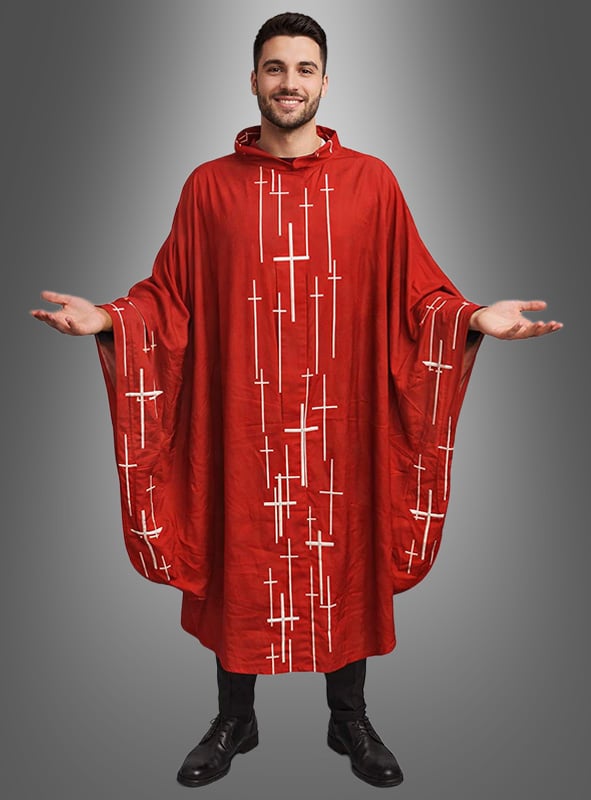 Ein Mann steht lächelnd mit ausgebreiteten Armen da; er trägt ein rotes Priester-Messgewand mit Kreuzen, das als Karnevalskostüm gestaltet und mit vertikalen und horizontalen weißen Streifen verziert ist, vor einem grauen Hintergrund mit Farbverlauf.