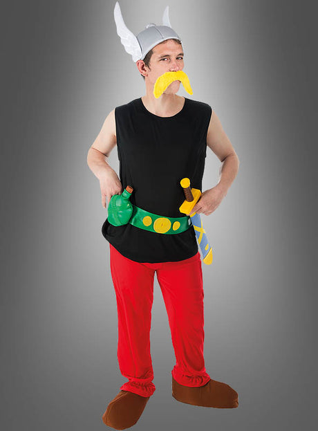 Ein Mann in einem Wikinger-Kostüm im Cartoon-Stil mit geflügeltem Helm, gelbem Schnurrbart, schwarzem Hemd, roter Hose, braunen Schuhen und einem grünen Gürtel mit Spielzeugschwert vor grauem Hintergrund – perfekt für Ihre nächste Mottoparty als „Deluxe Asterix-Kostüm für Erwachsene“ (Original-Lizenz) oder als auffälliges Fasching-Kostüm.