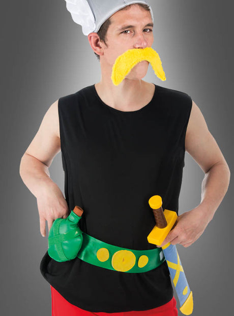 Eine Person im „Deluxe Asterix-Kostüm für Erwachsene“ (Original-Lizenz): bestehend aus einem schwarzen, ärmellosen Shirt, einer roten Hose, einer weißen Kochmütze und einem übergroßen gelben Schnurrbart – komplett mit Spielzeugschwert und grüner Flasche, die an einem gelben Gürtel befestigt sind. Ideal als Fasching-Kostüm oder für Themenpartys.