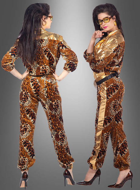 Zwei Frauen posieren in „80er Trainingsanzug Glamping Panther“-Jumpsuits mit schwarzen Gürteln und High Heels vor einem grauen Hintergrund mit Farbverlauf – die perfekte Kleidung für jede 80er-Jahre-Mottoparty.
