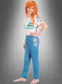 Ein Kind im Nami-Kostüm aus „One Piece“, inspiriert von der Strohhut-Bande, mit einer orangefarbenen Perücke, einem weißen Hemd mit türkisfarbenen Mustern und einer blauen Hose mit weißen und orangefarbenen Kreisen, steht barfuß vor einem grauen Hintergrund mit Farbverlauf.