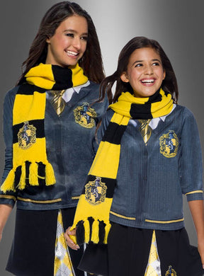 Zwei Mädchen, die identische Harry-Potter-Kostüme und den gelben Hufflepuff-Schal aus der Harry-Potter-Reihe tragen, stehen lächelnd nebeneinander vor einem grauen Hintergrund mit Farbverlauf. Beide tragen diese offiziell lizenzierten Accessoires und verkörpern damit perfekt die Magie und den Geist des Hauses Hufflepuff.