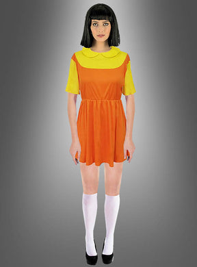 Eine Person trägt das „Kinderspiel Puppe“-Kostüm – „Squad Game“, ein kurzes orange-gelbes Kleid, das vom legendären „Rotes Licht, Grünes Licht“-Kleid inspiriert ist, dazu weiße Kniestrümpfe und schwarze Schuhe; sie steht vor einem grauen Hintergrund mit Farbverlauf.