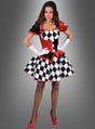 Eine Frau, die das „Deluxe Harlekin Clown Kleid“ trägt – ein auffälliges Kostüm in Rot-, Schwarz- und Weißtönen mit Puffärmeln, einem karierten Rock, weißen Handschuhen, Netzstrümpfen und roten High Heels –, posiert vor einem grauen Hintergrund mit Farbverlauf. Dieses sexy Damenkostüm verbindet auf meisterhafte Weise verspieltes Zirkusflair mit raffinierter Eleganz.