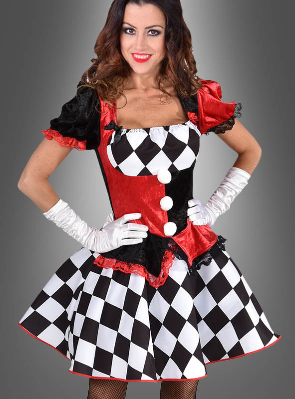 Eine Frau trägt das „Deluxe Harlekin Clown Kleid“ mit auffälligen roten, schwarzen und weißen Rautenmustern, ergänzt durch weiße Handschuhe und einen kurzen Rock, während sie vor einem grauen Hintergrund mit Farbverlauf steht. Dieses auffällige Kostüm eignet sich perfekt für jede Veranstaltung oder Kostümparty zum Thema Zirkus.
