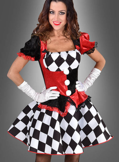 Eine Frau trägt das „Deluxe Harlekin Clown Kleid“ mit auffälligen roten, schwarzen und weißen Rautenmustern, ergänzt durch weiße Handschuhe und einen kurzen Rock, während sie vor einem grauen Hintergrund mit Farbverlauf steht. Dieses auffällige Kostüm eignet sich perfekt für jede Veranstaltung oder Kostümparty zum Thema Zirkus.