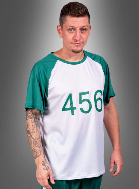 Eine Person mit kurzen Haaren und einem Spitzbart trägt das „T-Shirt Game Spieler Nummer 456 Herren“, das weiß und grün ist und auf der Vorderseite die Nummer 456 vor einem grauen Hintergrund zeigt.