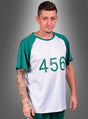 Eine Person mit kurzen Haaren und einem Spitzbart trägt das „T-Shirt Game Spieler Nummer 456 Herren“, das weiß und grün ist und auf der Vorderseite die Nummer 456 vor einem grauen Hintergrund zeigt.