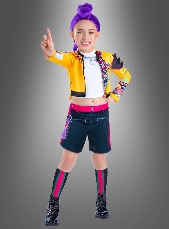 Ein Kind mit lila Haaren, die zu einem Dutt hochgesteckt sind, trägt das K-Pop-„Demon Hunters“-Kinderkostüm „Rumi“ – bestehend aus einer gelben Jacke, einem weißen Hemd, schwarzen Shorts, kniehohen Socken und schwarzen Stiefeln – und steht vor einem grauen Hintergrund, wobei es mit der rechten Hand das Peace-Zeichen macht und dabei energiegeladenen Stil und verspielten Charme ausstrahlt.