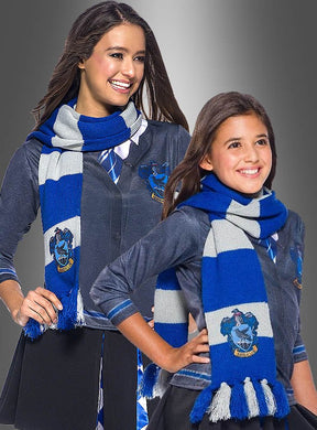 Vor einem grauen Hintergrund mit Farbverlauf stehen zwei Mädchen, die blau-grau gestreifte Schals mit dem Ravenclaw-Wappen, dunkle Hemden und Krawatten tragen. Ihr „Ravenclaw-Schal blau Harry Potter“ verleiht ihren Outfits einen Hauch von Magie, wodurch sich diese Szene perfekt für alle Fans eignet, die auf der Suche nach authentischem Harry-Potter-Kostümzubehör sind.