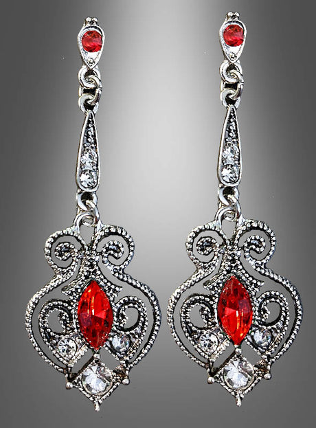 Ein Paar Ohrringe im Antik-Stil mit Edelsteinen, gefertigt aus kunstvoll verziertem Silber mit roten und klaren Edelsteinen, mit filigranen Wirbelmustern und hängenden Elementen, präsentiert vor einem grauen Hintergrund mit Farbverlauf.