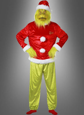 Eine Person, die das 5-teilige „Der Grinch“-Kostüm trägt – bestehend aus einer roten Weihnachtsmütze und einer roten Jacke sowie einer gelbgrünen Pelzmaske und Handschuhen –, steht mit in die Hüften gestützten Armen vor einem grauen Hintergrund mit Farbverlauf.