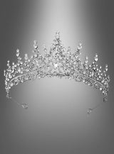 „Luxus Krone für Königin“ – eine silberne Tiara, verziert mit filigranen, funkelnden Kristall- und Edelsteinakzenten, die an eine Königin-Krone oder ein Diadem aus Gold und Silber erinnern, elegant präsentiert vor einem grau verlaufenden Hintergrund.