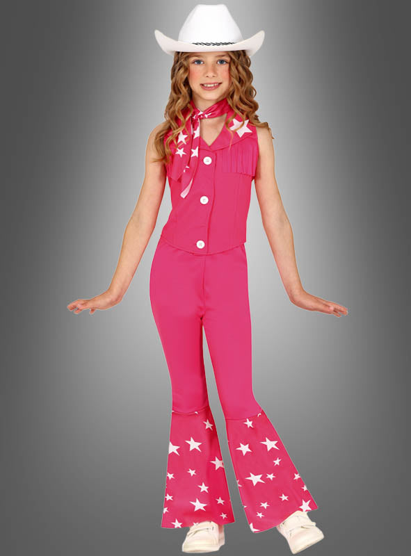 Ein Kind im „Pink Cowgirl“-Kostüm für Mädchen – mit einem rosa Cowboy-Outfit, das mit weißen Sternen verziert ist, einem weißen Hut und einem passenden Schal – posiert fröhlich mit ausgestreckten Armen vor einem grauen Hintergrund mit Farbverlauf. Dieses bezaubernde Ensemble eignet sich perfekt für jede Veranstaltung im Barbie-Style-Western-Kostüm-Stil.