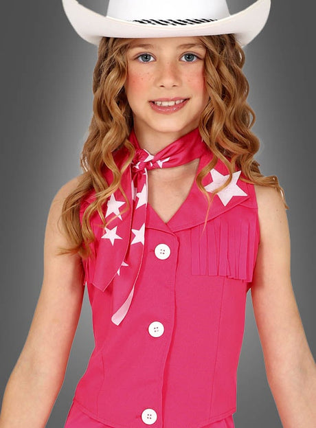 Ein junges Mädchen, das das „Pink Cowgirl“-Kostüm für Mädchen trägt – einen weißen Cowboyhut, ein rosa Outfit mit weißen Knöpfen und einen rosa Schal mit weißen Sternen –, posiert vor einem grauen Hintergrund; perfekt als Kinderkostüm für Mädchen oder für alle, die den ultimativen Western-Look im Barbie-Stil suchen.
