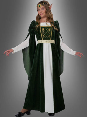 Eine Person, die das Mittelalterkleid „Elfenprinzessin Flora“ trägt – ein grün-weißes Kleid mit langen Ärmeln, einem verzierten Gürtel, spitzen Elfenohren, einem Kopfschmuck und schwarzen Schuhen –, steht vor einem grauen Hintergrund.