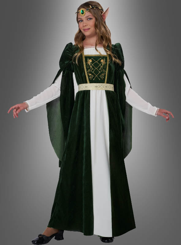 Eine Person, die das Mittelalterkleid „Elfenprinzessin Flora“ trägt – ein grün-weißes Kleid mit langen Ärmeln, einem verzierten Gürtel, spitzen Elfenohren, einem Kopfschmuck und schwarzen Schuhen –, steht vor einem grauen Hintergrund.