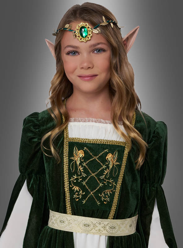 Ein junges Mädchen, das das Mittelalterkleid „Elfenprinzessin Flora“ trägt – ein grün-weißes Kleid im mittelalterlichen Stil –, kombiniert mit spitzen Elfenohren und einem mit Edelsteinen besetzten Kopfschmuck, steht vor einem grauen Hintergrund.