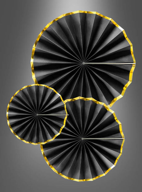 Drei schwarz-goldene Papierrosetten (23–43 cm) mit eleganten goldenen Rändern sind als stilvolle Hängedekoration für eine Party vor einem grauen Farbverlauf angeordnet.