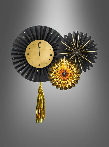 Drei schwarze und goldene Papierrosetten (23–43 cm), darunter eine in Form einer Mitternachtsuhr, werden vor einem grauen Hintergrund mit Farbverlauf präsentiert. Diese stilvollen Hängedekorationen zeichnen sich durch schwarz-goldene Akzente und metallische Quasten aus und sind damit die perfekte festliche Ergänzung für jede Feier.