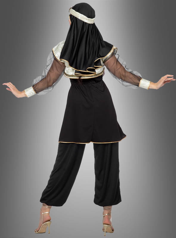 Eine Person steht mit dem Rücken zur Kamera und trägt das Kostüm „Orient Prinzessin Jasmina aus 1001 Nacht“ mit schwarzen und goldenen Details, transparenten Ärmeln, einem Kopfschmuck, einer weiten Hose und hochhackigen Schuhen vor einem grauen Hintergrund mit Farbverlauf.