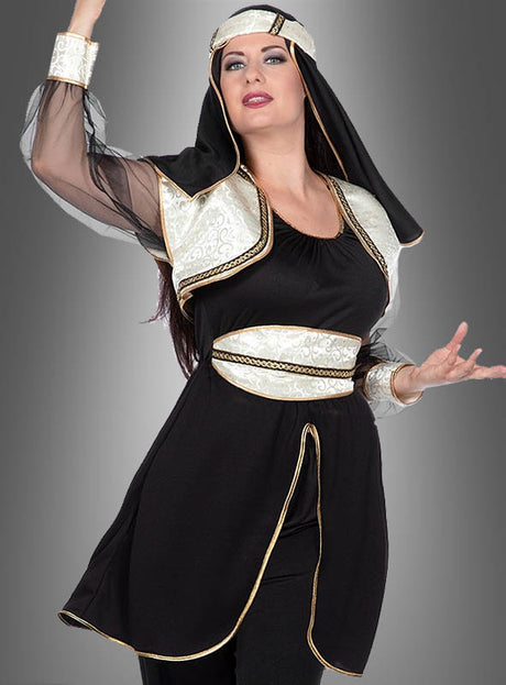 Eine Frau posiert mit erhobenem Arm vor einem grauen Hintergrund und trägt das elegante schwarz-goldene Kostüm „Orient Prinzessin Jasmina aus 1001 Nacht“ mit transparenten Ärmeln und einem passenden Kopfschmuck.