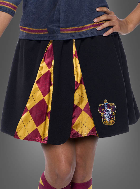 Eine Person trägt das „Gryffindor Rock für Damen“ aus der Harry-Potter-Reihe mit rot-goldenen Einsätzen im Rautenmuster und einem aufgenähten Gryffindor-Wappen, die Hände in die Hüften gestützt vor einem schlichten Hintergrund – ideal, um Ihre Harry-Potter-Schuluniform oder Ihr Gryffindor-Kostüm zu vervollständigen.