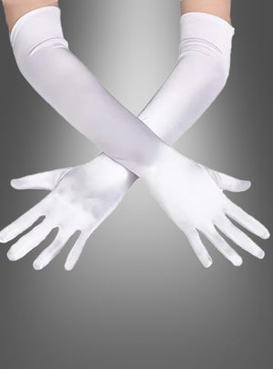 Ein Paar Arme, an denen lange, weiße Satinhandschuhe in verschiedenen Farben getragen werden, sind an den Handgelenken vor einem grauen Hintergrund mit Farbverlauf gekreuzt.