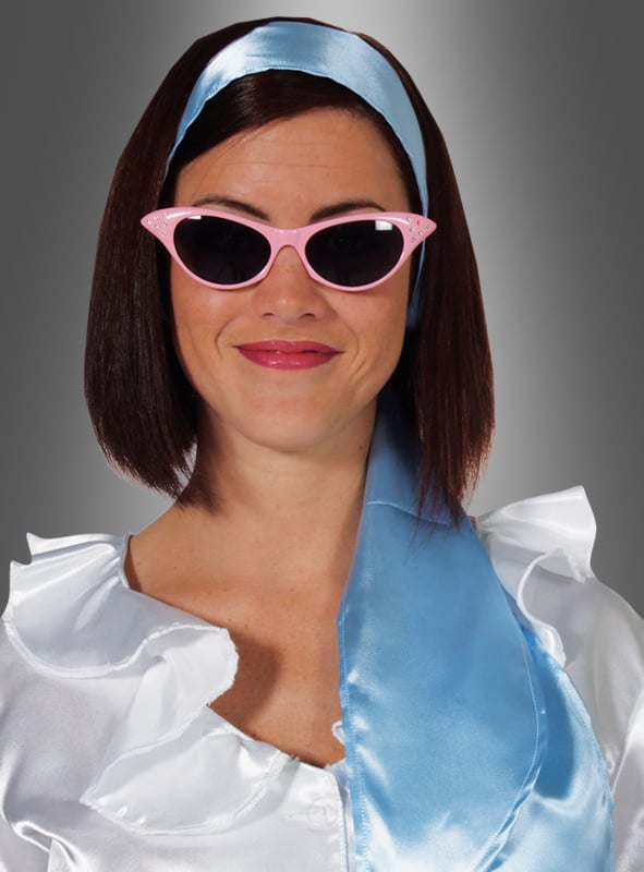 Eine Frau lächelt vor einem grauen Hintergrund. Sie trägt eine weiße Rüschenbluse, das „Haarband Halstuch Satin“ in Blau, das sowohl als Haarband als auch als Halstuch dient, sowie eine rosa Cat-Eye-Sonnenbrille – ein perfekter Look für jede 70er-Jahre-Party.
