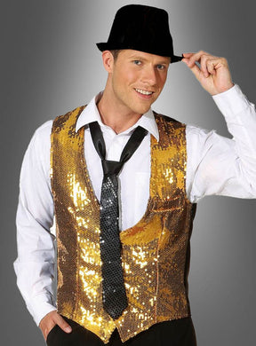 Ein Mann mit schwarzem Fedora, weißem Hemd, loser schwarzer Krawatte und der goldenen „Pailletten-Weste für Herren“ lächelt und tippt an seinen Hut vor einem grau verlaufenden Hintergrund.