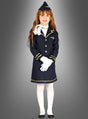 Ein Kind steht mit dem Gesicht nach vorne, gekleidet im Stewardess-Kinderkostüm – eine marineblaue Pilotenuniform mit goldenen Verzierungen, weißen Handschuhen, weißen Strumpfhosen, schwarzen Schuhen und einer passenden Mütze –, perfekt für den Karneval oder als Stewardess-Kostüm für Mädchen – vor einem grauen Hintergrund mit Farbverlauf.