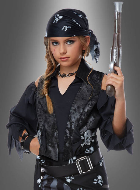 Ein Kind trägt ein „Totenkopf-Piratin“-Kinderkostüm, bestehend aus einem schwarzen Bandana und einer Weste mit Totenkopfmotiven, hält eine Spielzeug-Steinschlosspistole in der Hand und steht vor einem grauen Hintergrund mit Farbverlauf.