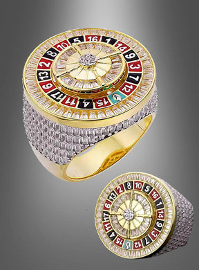 Ein Roulette-Rad aus 14-karätigem Gold von Edler Casino, das ein Roulette-Rad-Design mit farbigen Zahlen auf der Oberseite zeigt und aus zwei verschiedenen Blickwinkeln vor einem grauen Hintergrund dargestellt ist.