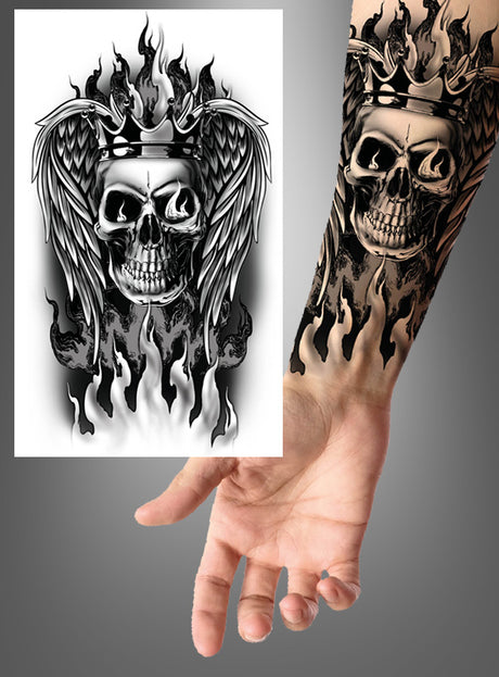 Ein gruseliges Motiv aus unserem Produkt „Tattoo – verschiedene Designs“: Das Bild zeigt ein Tattoo auf dem Unterarm, das einen lodernden Totenkopf mit Krone und Flügeln darstellt, direkt neben der ursprünglichen Schwarz-Weiß-Zeichnung.