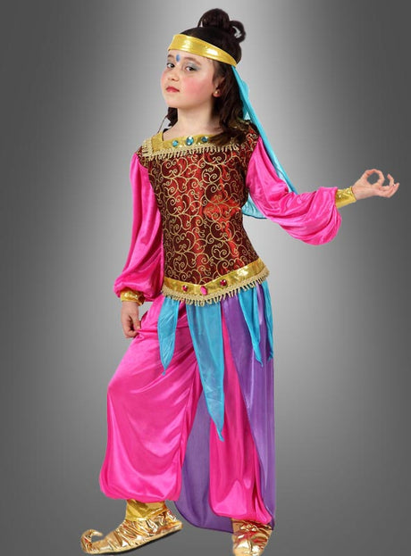 Ein Kind, das das farbenfrohe Kostüm „Orient Prinzessin für Kinder“ trägt – bestehend aus einer rosa Hose, einem gemusterten Oberteil, blauen und goldenen Akzenten sowie einem Stirnband –, posiert vor einem grauen Hintergrund.