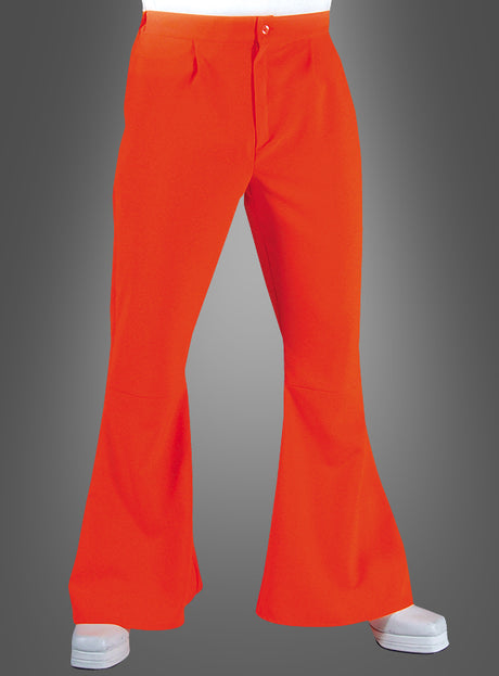 Eine Person, die eine leuchtend orangefarbene Hippie-Hose mit Schlag für Herren und weiße Schuhe trägt und mit gespreizten Beinen vor einem schlichten Hintergrund mit Farbverlauf steht, verkörpert perfekt den authentischen Retro-Stil der Herrenhosen aus den 70er Jahren.