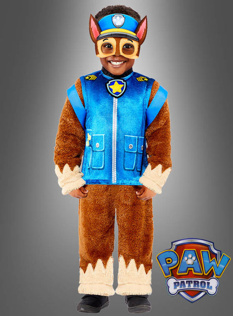 Ein Kind lächelt in seinem „Deluxe Chase Paw Patrol“-Kostüm, das aus einer blauen Weste, braunen, pelzigen Ärmeln und Hosen sowie einer passenden Maske besteht – genau wie der tapfere Polizeihund aus der Serie. Das Kinderkostüm ist an der Ecke mit dem Paw Patrol-Logo versehen und sorgt so für einen authentischen Look.