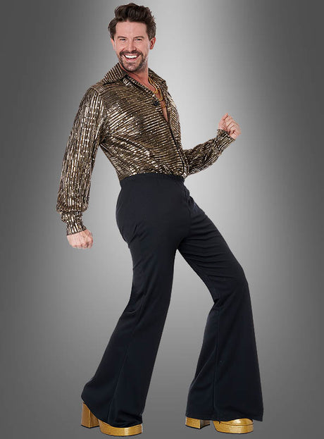 Ein Mann präsentiert das „Disco Fever“-Herrenkostüm in Gold und Schwarz, bestehend aus einem glänzenden goldenen Hemd, einer schwarzen Schlaghose und goldenen Plateauschuhen, während er vor einem grauen Hintergrund mit Farbverlauf eine energiegeladene Pose einnimmt – und damit den pulsierenden Disco-Spirit perfekt einfängt.