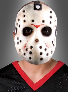 Eine Person trägt die Jason-Voorhees-Maske aus „Freitag, der 13.“ mit schwarzen und roten Markierungen, dazu ein schwarzes Netzshirt mit rotem Rand, vor einem grauen Hintergrund mit Farbverlauf – ein auffälliger Look, perfekt für Horrorfilmfans und Liebhaber von „Freitag, der 13.“.