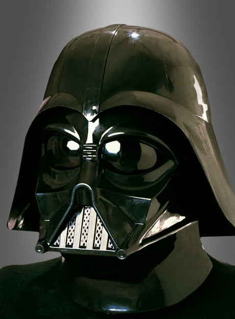 Eine Person, die den originalen Darth-Vader-Helm aus „Star Wars“ trägt – dessen glänzende Oberfläche an die Kultfigur erinnert –, steht vor einem neutralen Hintergrund mit Farbverlauf.