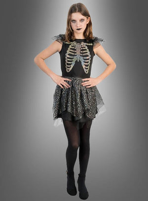 Vor einem grauen Hintergrund steht eine Person, die das „Schillerndes Skelett Kleid Mädchen“ mit seinem auffälligen Skelett-Print trägt, kombiniert mit schwarzen Strumpfhosen und dunklem Make-up – die perfekte Inspiration für alle, die auf der Suche nach einem auffälligen Halloween-Kostüm für Mädchen sind.