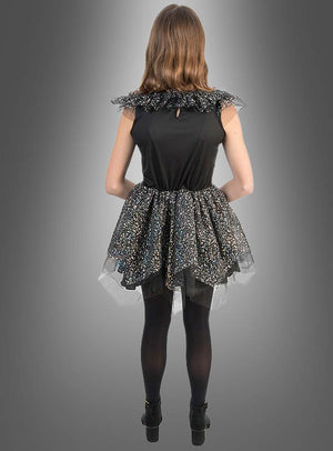 Eine Person steht mit dem Rücken zur Kamera und trägt ein schwarzes, ärmelloses „Schillerndes Skelett Kleid Mädchen“ mit einem mehrlagigen, glitzernden Rock, kombiniert mit schwarzen Strumpfhosen und Schuhen vor einem grauen Hintergrund mit Farbverlauf. Dieser Halloween-Kostüm-Look für Mädchen ist sowohl stilvoll als auch gruselig.