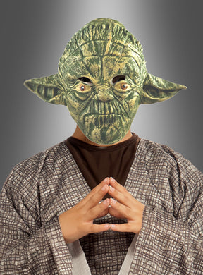 Eine Person, die eine Yoda-Maske „STAR WARS für Erwachsene“ trägt, steht mit gefalteten Händen vor einem grauen Hintergrund mit Farbverlauf und verkörpert die Weisheit eines wahren Jedi-Meisters.