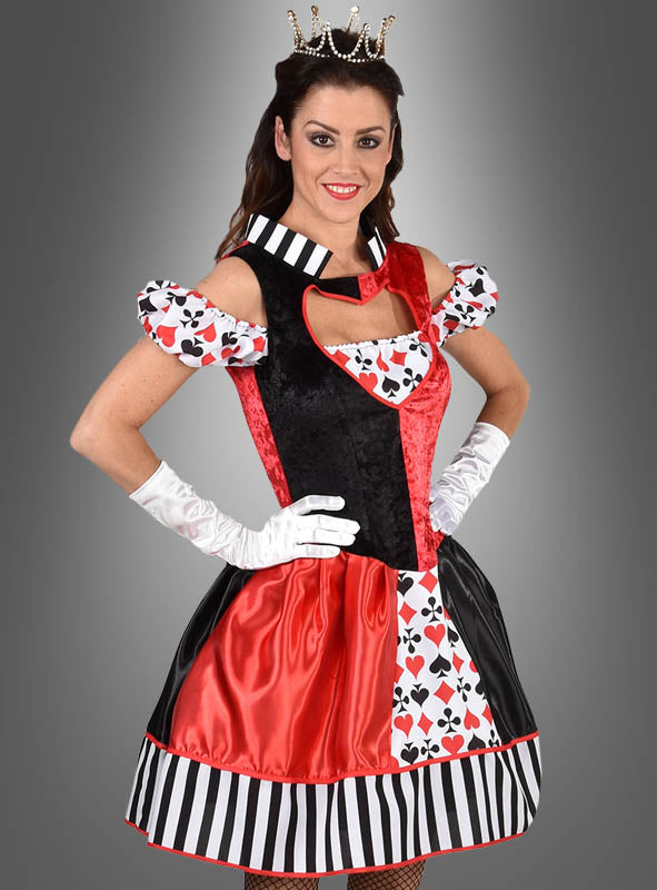 Vor einem grauen Hintergrund mit Farbverlauf steht eine Frau, die ein auffälliges „Deluxe Kartenkönigin“-Kleid trägt, das mit Kartensymbolen, einer Krone, weißen Handschuhen und einem schwarz-rot-weißen Kleid verziert ist, das an ein „Casino Kartenspiel“-Kleid erinnert.