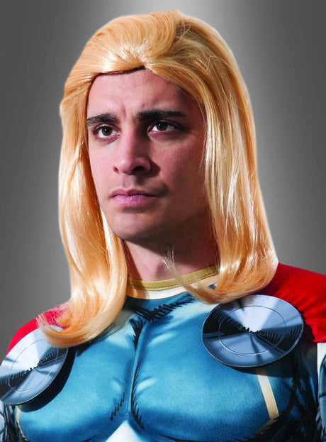 Eine Person in einem Superheldenkostüm mit blauer Brust, rotem Umhang und einer langen blonden Thor-Superheldenperücke blickt vor einem grauen Hintergrund nach vorne.
