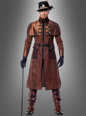 Vor einem grauen Hintergrund steht ein Mann, der den „Deluxe Steampunk Mantel Montgomery“, hohe Stiefel, Handschuhe und einen schwarzen Hut mit einer Feder trägt und einen Spazierstock in der Hand hält.
