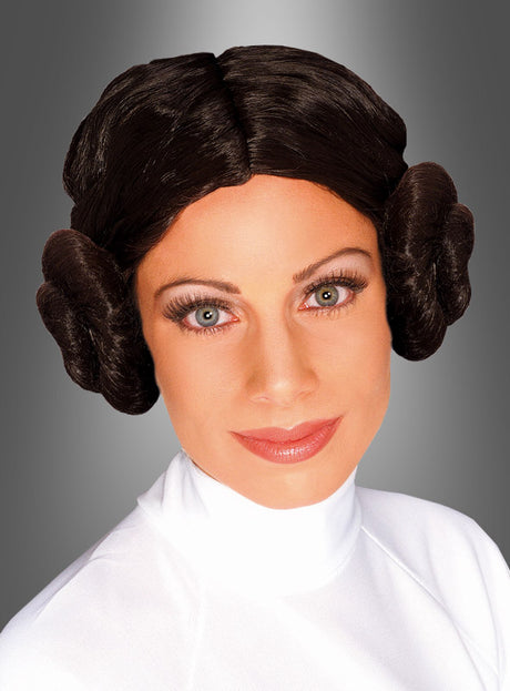 Eine Frau in einem weißen Kostüm, die die „Prinzessin Leia“-Perücke aus „Star Wars“ mit braunen Haaren trägt, die zu zwei charakteristischen seitlichen Dutts frisiert sind, blickt vor einem grauen Hintergrund mit Farbverlauf in die Ferne – ein idealer Look für jedes „Star Wars“-Kostüm oder jede Cosplay-Veranstaltung mit Original-Lizenzware.